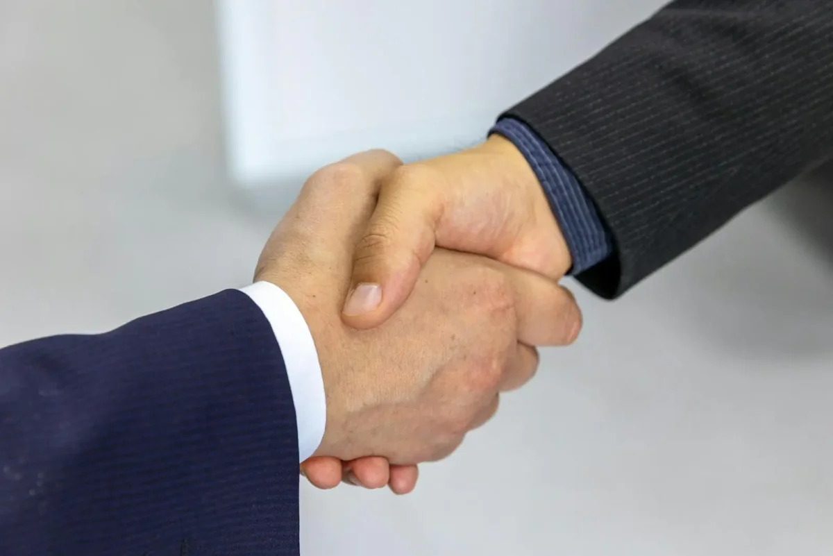 Close-up of two business professionals shaking hands in dark suits